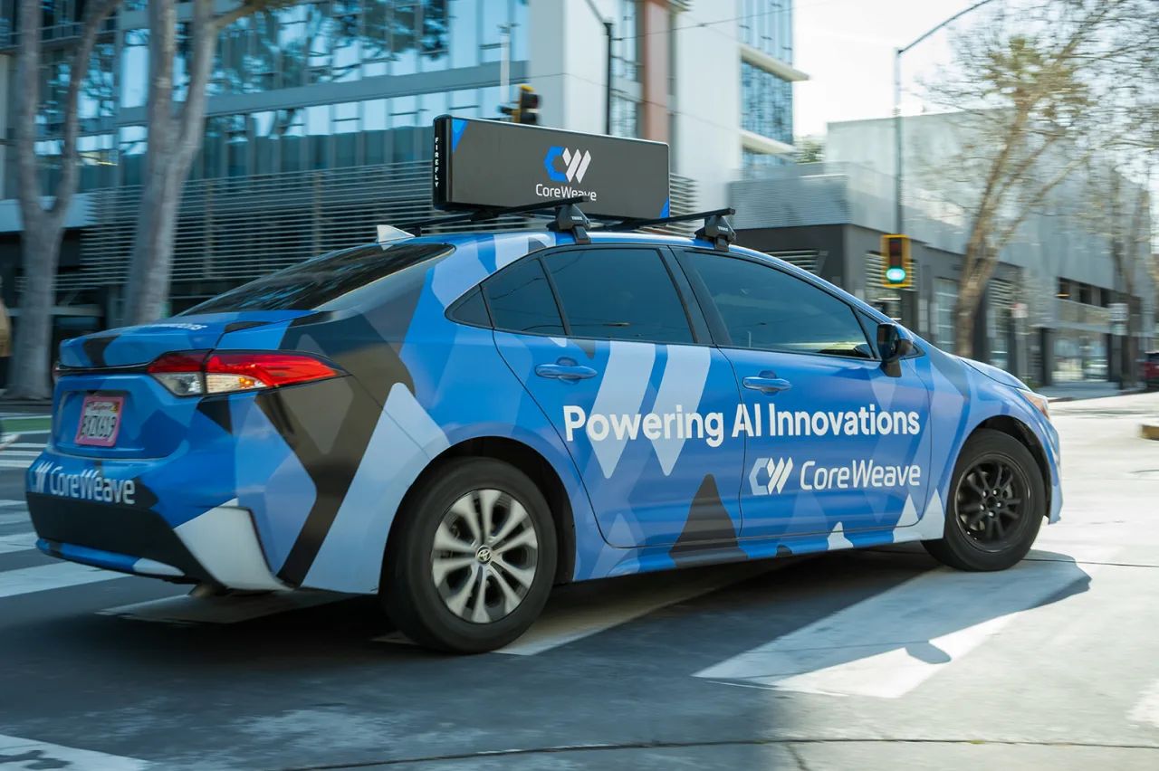 A car wrapped in CoreWeave blue reading Powering AI Innovations
