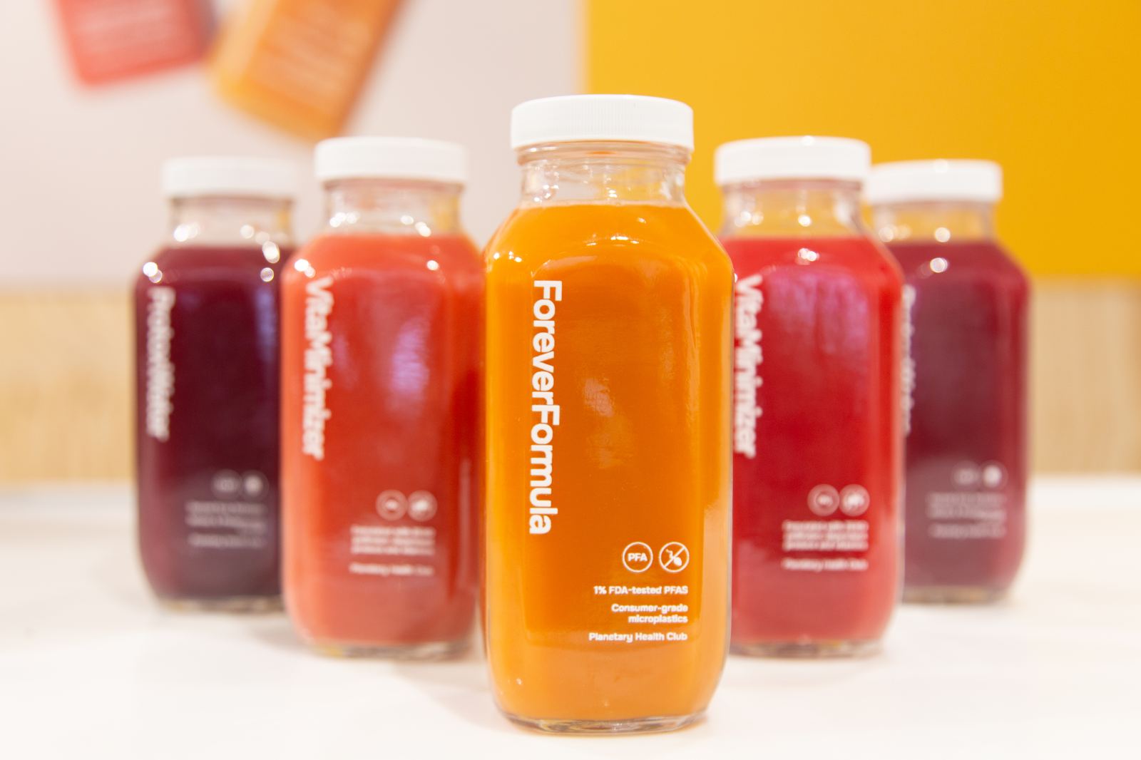 A row of Planetary Health Club juice bottles led by Forever Formula