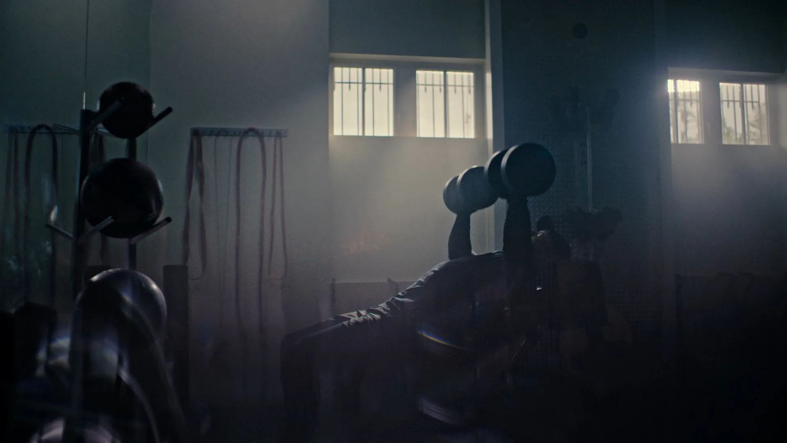A dumbbell press in a dim, misty gym