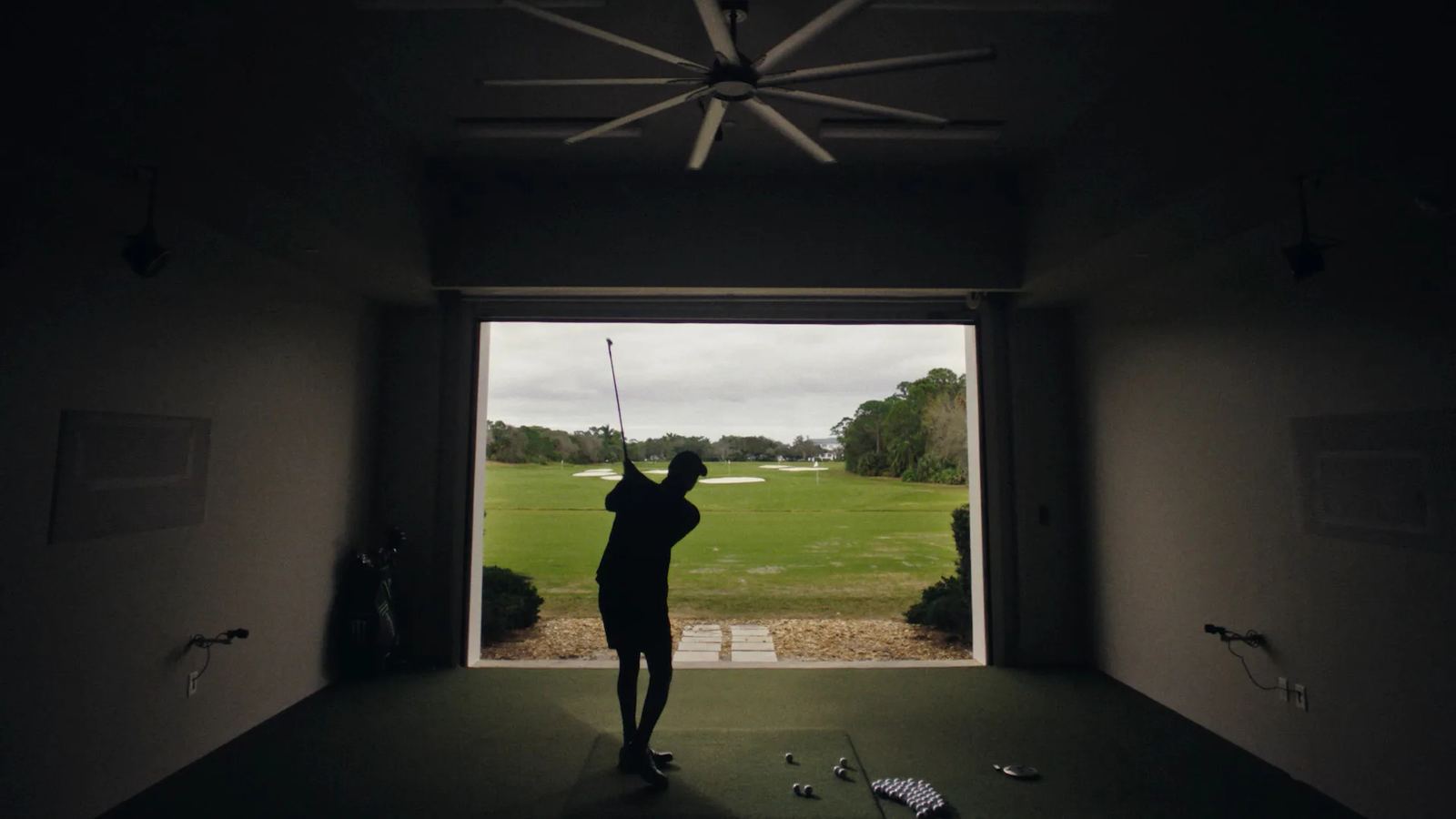 Silhouette of a golfer swinging in an open bay facing the course